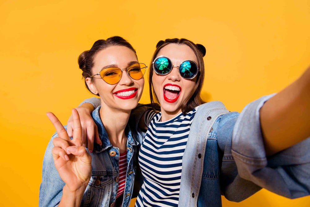 Two friends smiling and giving the peace sign