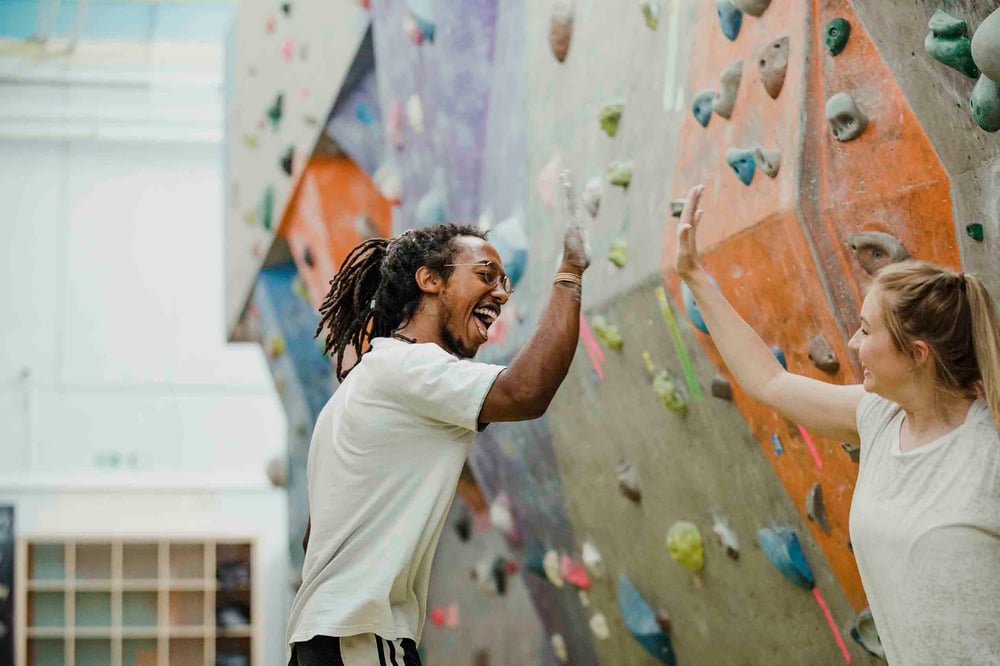People high fiving at a rock climbing gym
